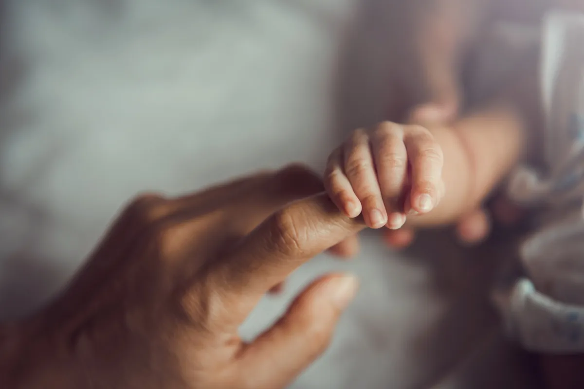 Kleine Babyhand hält einen Finger fest